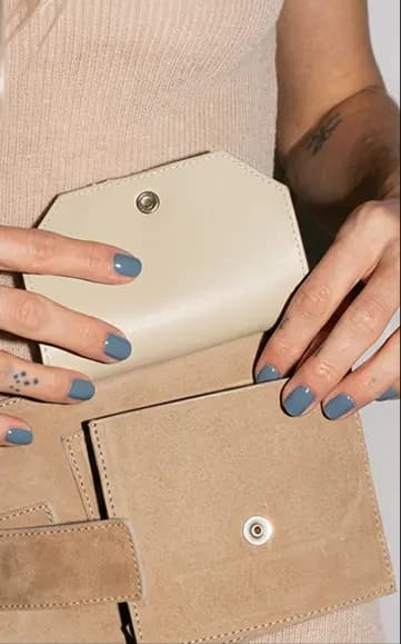 Hands with Blue No. 2 nails opening a suede wallet